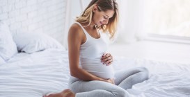 Attractive,Pregnant,Woman,Is,Sitting,In,Bed,And,Holding,Her