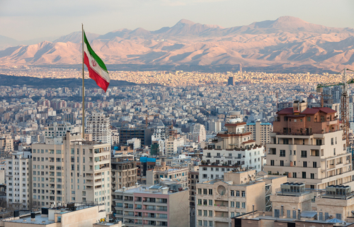 Waving,Iran,Flag,Above,Skyline,Of,Tehran,At,Sunset.